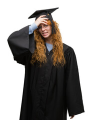Young redhead student woman wearing graduated uniform stressed with hand on head, shocked with...