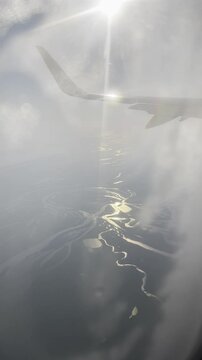 Vertical view from above of river through cloudy sky from blurred plane porthole