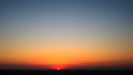 Vintage sunset gradient with burnt orange and golden yellow blending into a soft blue sky