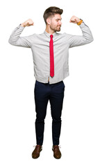 Young handsome business man showing arms muscles smiling proud. Fitness concept.