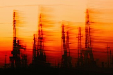 Obraz premium Abstract silhouettes of oil rigs against a vibrant sunset, showcasing the dynamic nature of the energy industry. Concept of energy and industrial landscape.
