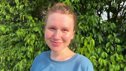 Young happy woman enjoying sunny weather and fresh air in front of green eco wall