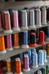A vibrant shelf with colorful spools of thread in an atelier. embroidery, textile production, and design tools. craftsmanship, sewing, clothing brands,  small businesses and the art of textile work