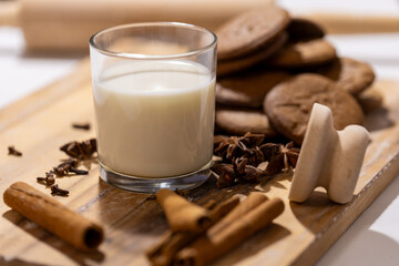 a glass of milk with cinnamon, anise and other spices, gingerbread and wooden cookie cutter 