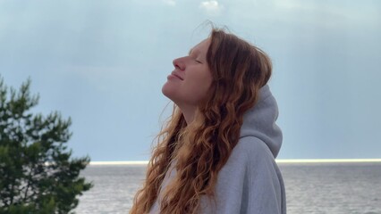 Young woman enjoying weather on sea, beach, breath deep fresh air, raise her arms at rain