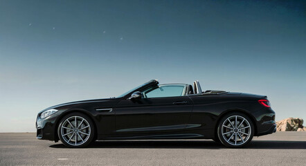 Sleek black convertible car against a clear blue backdrop, automotive elegance