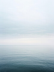 Obraz premium A foggy morning view of a vast, calm ocean with the horizon barely visible, blending soft pastel hues into serene tranquility. Generative AI