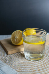 A glass of water with lemon on a cozy kitchen table, evoking warmth and comfort.