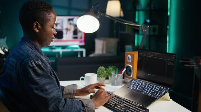 Teleworker in living room office using laptop to do coding for software developing, handheld camera shot. Remote employee typing on device keyboard, solving tasks in apartment, camera B close up
