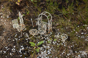 A charming and colorful miniature scene featuring wire garden furniture set in nature