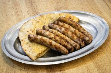 Grilled Sausages with Flatbread Somun on a Metal Plate - Traditional Balkan Meal