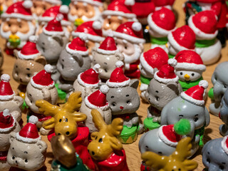 Una adorable colección de figuritas de animales de cerámica como renos y gatos con sombreros de Papá Noel se exhibe en un mercado de decoración navideña