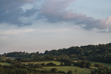 Beautiful green hills covered with forests under clouds in a blue sky