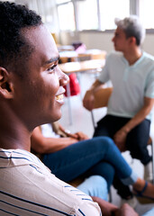 Vertical. Group of multiracial high school students sitting on chairs in circle and interacting in classroom. Cooperation male classmates, listening and sharing questions meeting in support class 