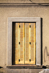 Window with closed beautiful old metal yellow shutters