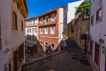 A picturesque street intersection in the historic center of Coimbra, Portugal, with colorful buildings, cobblestone streets, and a lively atmosphere