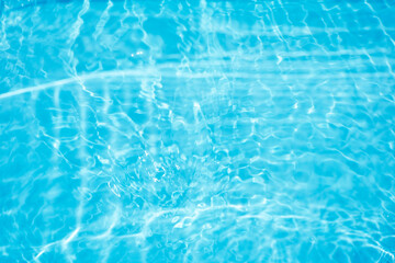 Blue water with ripples on the surface. Defocus blurred transparent blue colored clear calm water surface texture with splashes and bubbles. Water waves with shining pattern texture background.