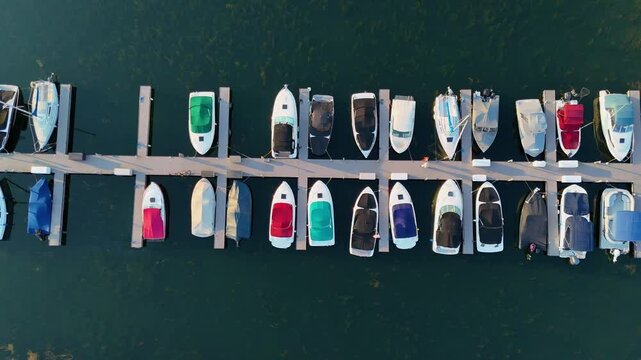 Discover the serene beauty of the small boat harbor in Buffalo, NY, with this captivating aerial drone footage. The camera glides directly above a row of parked boats, smoothly tracking down the dock.