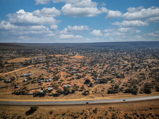 aerial view african landscape, highway and village across the road, savannah plain with acacia trees and bush , sunny afternoon