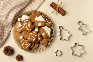 Plate with gingerbread and cutters on beige background. Christmas concept. Flat lay, top view