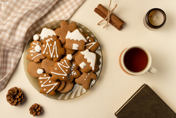 Coziness composition with gingerbread, cup of tea and book on beige background. Christmas concept. Flat lay, top view.