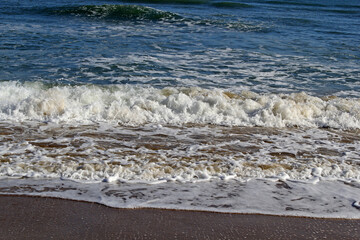 Close-up of waves rolling in towards the shore of a sandy beach