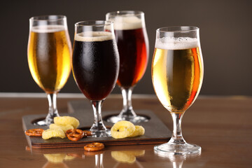 Glasses with different types of beer and snacks on table, closeup
