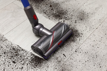 Cleaning floor with cordless vacuum cleaner indoors, closeup