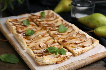 Tasty puff pastry pie with pears and mint on wooden table, closeup