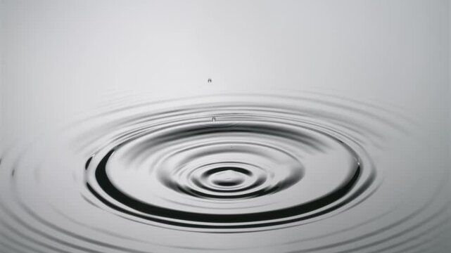 A single drop of water falling into a pool of water in slow motion.