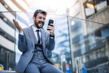 Successful Businessman Celebrating Good News on Smartphone Outdoors