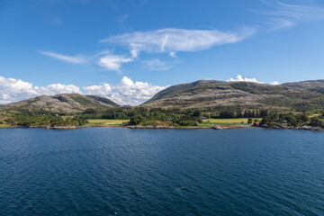 Obraz premium Beautiful Green Farm Land Along the Coast in Northern Norway near Kråkøya, in the Horsvær Area, Midsummer Day, Puffy Clouds