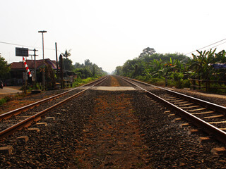 Naklejka premium View of the intersection between two railway tracks and a road on a sunny day.