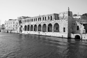 A black and white photo of a building with a river in the background