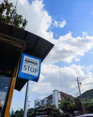 A bus stop sign on the post against the blue sky, located at a bus stop, blue sign