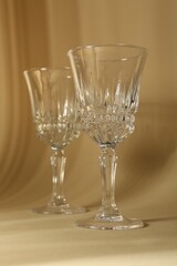 Two empty wine glasses on beige background