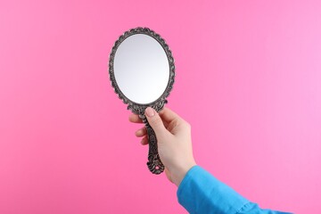 Woman holding beautiful mirror on pink background, closeup