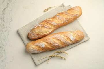 Fresh baguettes and spikes on beige textured table, flat lay