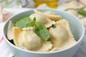 Delicious ravioli with cheese and basil served on white table, closeup