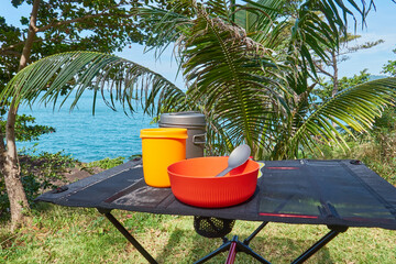 ultralight kitchen set for traveling on a folding table, in nature with a tropical view