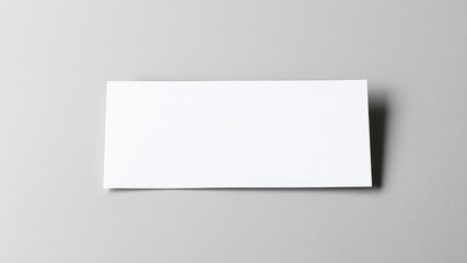 Fototapeta premium A blank white card resting on a gray surface, ready for your message or design.