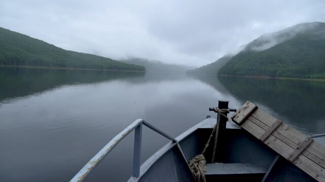 Zeya Reservoir. A boat sails along the calm waters of the lake among green coniferous hills.