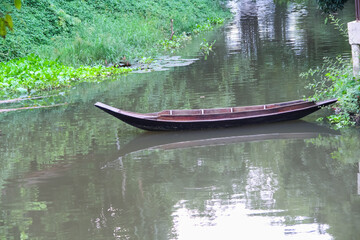 Single old blank wood boat with  shadow in the river on water background