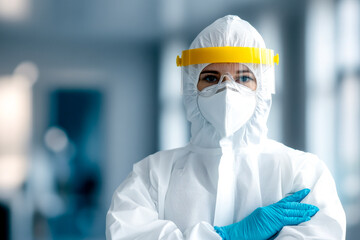 A healthcare worker in full PPE, including a mask and face shield, stands confidently in a modern medical facility, emphasizing safety and professionalism.