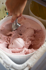 A view of a hand scooping strawberry ice cream.