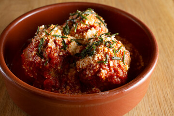A view of a small bowl of meatballs covered in romesco.