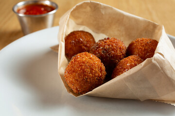 A view of a paper bag of arancini appetizers.