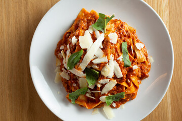 A top down view of a plate of pappardelle pasta with bolognese sauce.