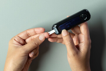 Woman's hands checking diabetes and hyperglycemia with digital blood sugar meter. Healthcare and...