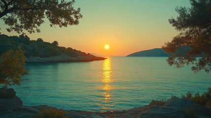 A scenic view of a sunrise over the water with the sun just above the horizon and a few trees framing the scene.